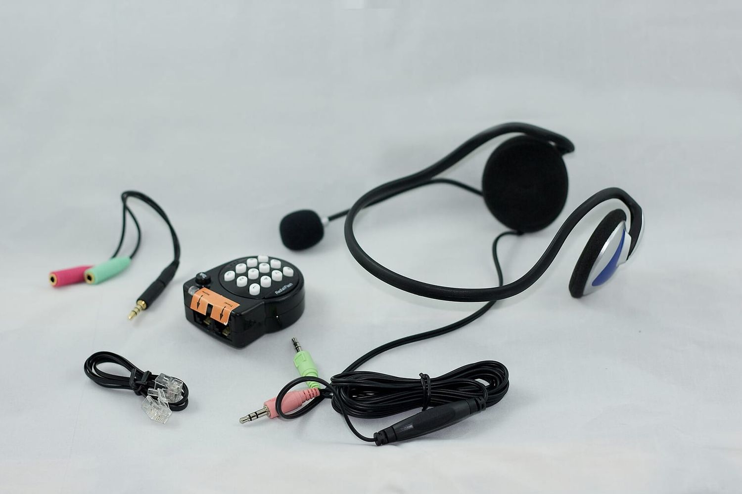 Headset mit Mikrofon, kleines Telefonmodul mit Tasten und Kabel auf hellem Grund